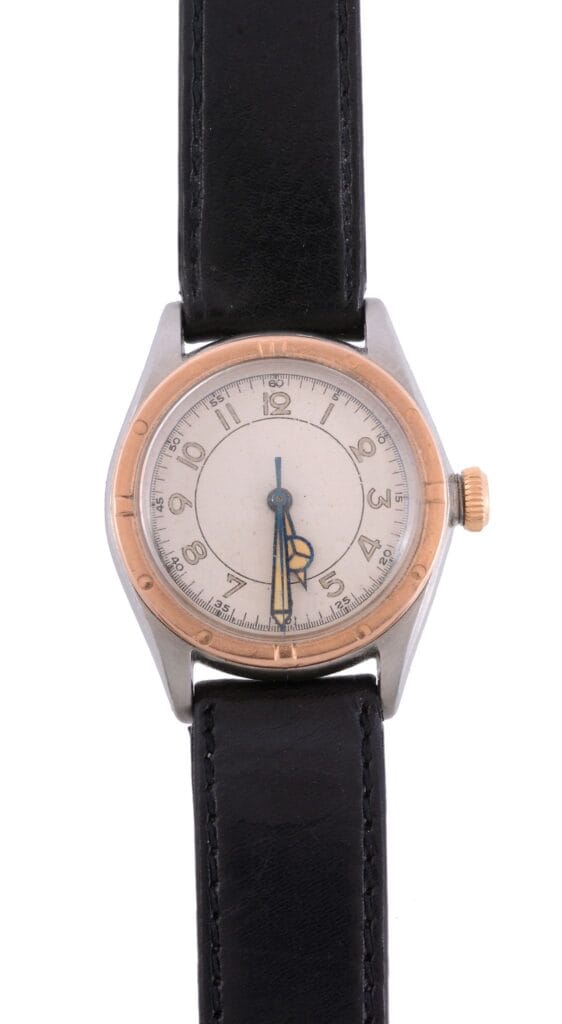 A vintage Rolex Oyster Perpetual wristwatch with a black leather strap and a round, silver and gold bezel.