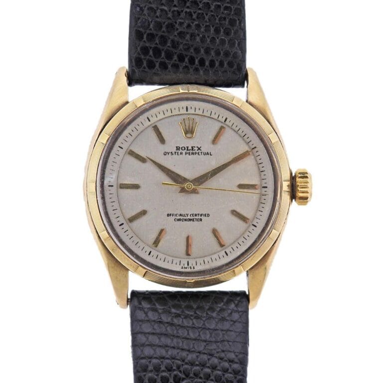 A vintage gold Rolex Oyster Perpetual 6585 watch featuring a black leather strap and a classic silver dial.