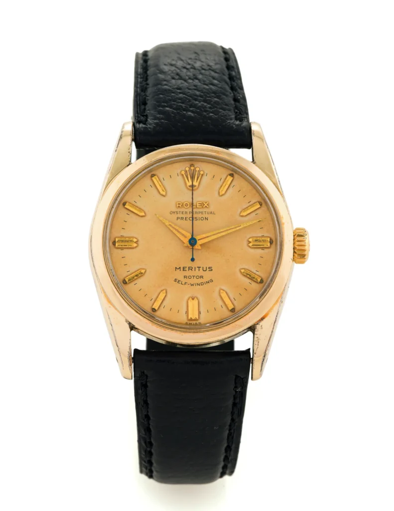 Gold Rolex Oyster Perpetual wristwatch, model 6594, with a black leather strap and MERITUS elegantly written on the dial.