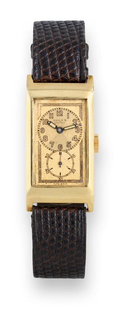 Vintage Rolex Prince gold rectangular wristwatch with a brown textured leather strap and an off-white dial.