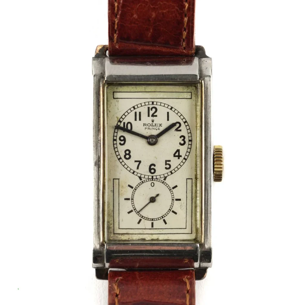A rectangular vintage Rolex Prince watch with a white dial, black numerals, and a brown leather strap.