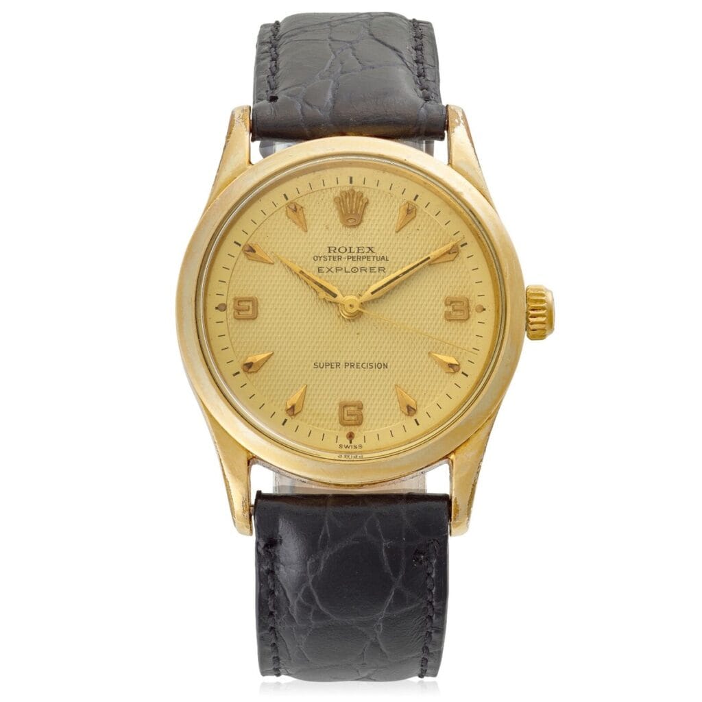Gold Rolex Explorer 5506 watch with a black leather strap and a cream-colored dial.