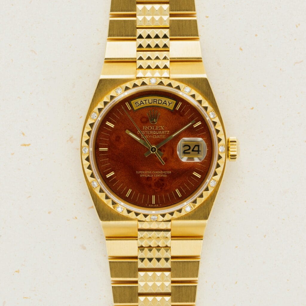 Gold Rolex Oysterquartz Day-Date 19038 wristwatch featuring a brown face, diamond hour markers, and a day-date display on a gold bracelet.