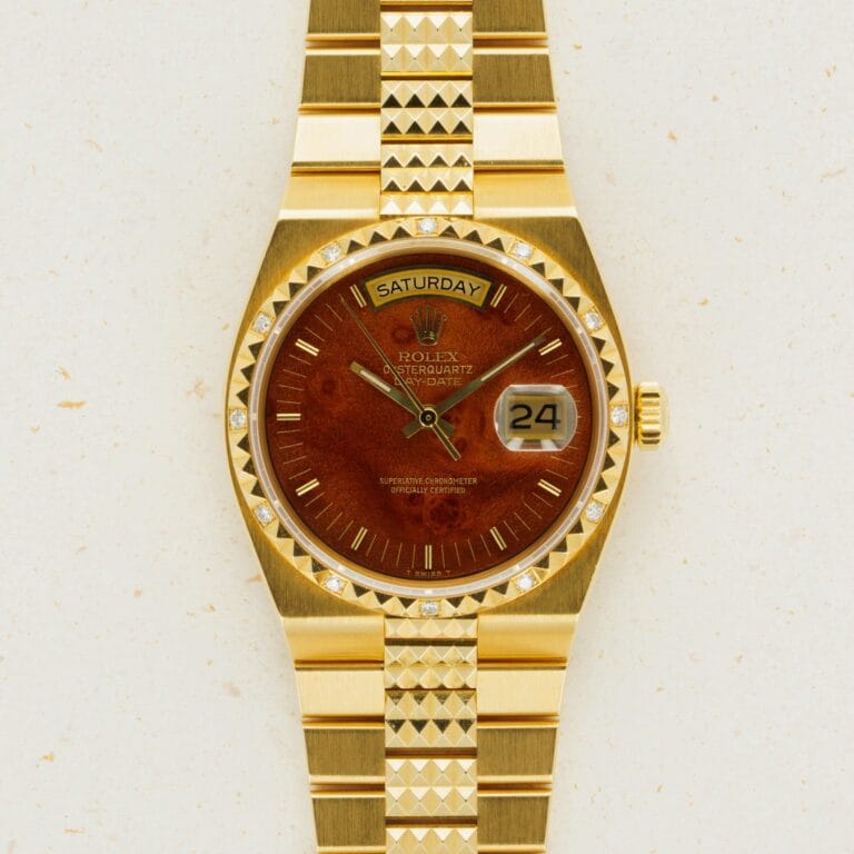 Gold Rolex Oysterquartz Day-Date 19038 wristwatch featuring a brown face, diamond hour markers, and a day-date display on a gold bracelet.