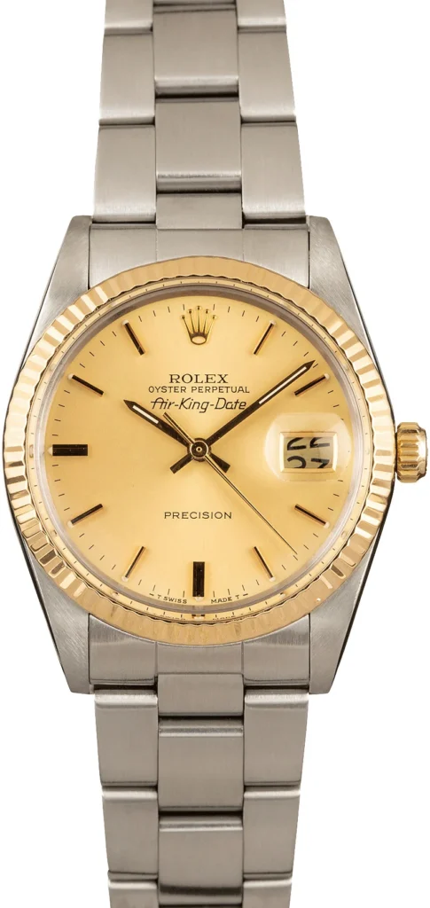 A Rolex Air-King Date watch, reference 5701, featuring a gold bezel, champagne dial, and silver metal bracelet.