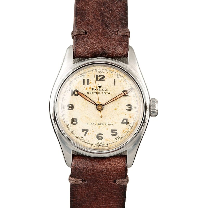 A vintage Rolex Oyster Royal 6044 watch featuring a brown leather strap and an aged white dial.