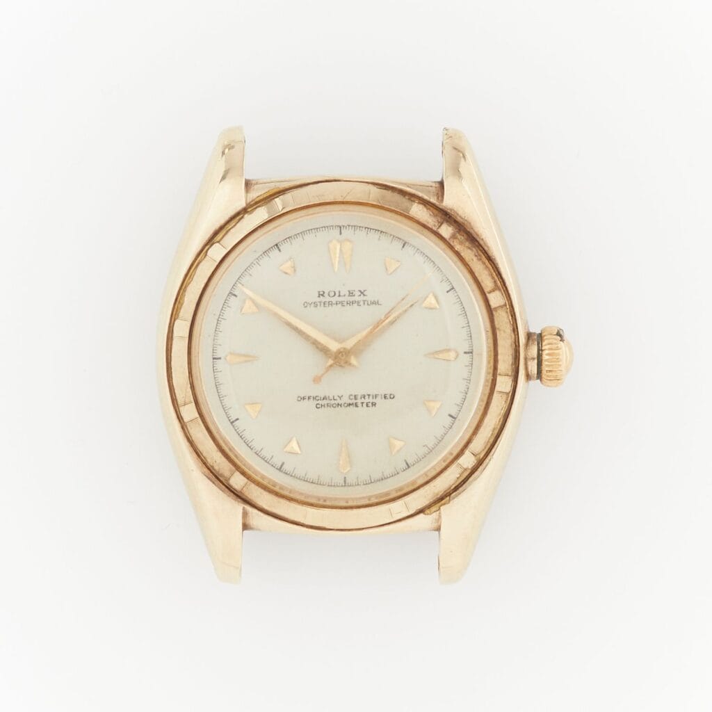 A vintage gold Rolex Oyster Perpetual wristwatch with a white dial and gold hour markers, photographed from above.