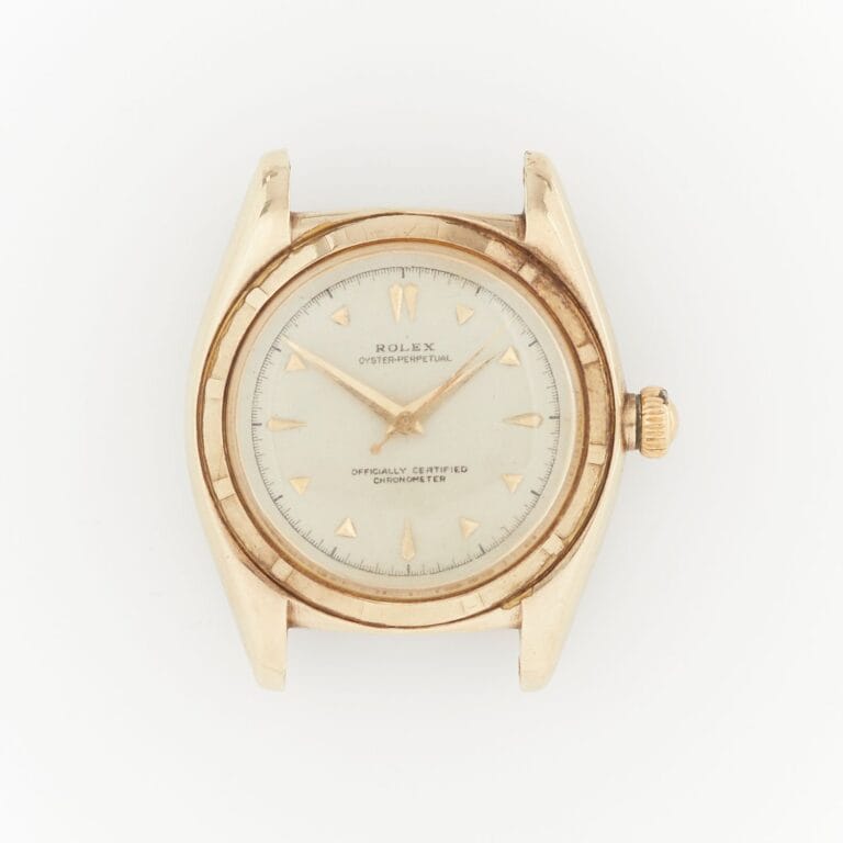 A vintage gold Rolex Oyster Perpetual wristwatch with a white dial and gold hour markers, photographed from above.