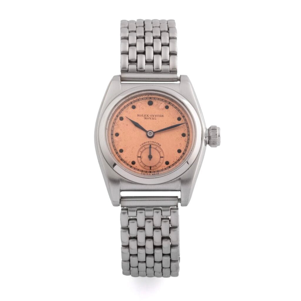 A vintage Rolex Oyster Royal wristwatch from 1873 featuring a pink dial, silver case, and metal link bracelet.