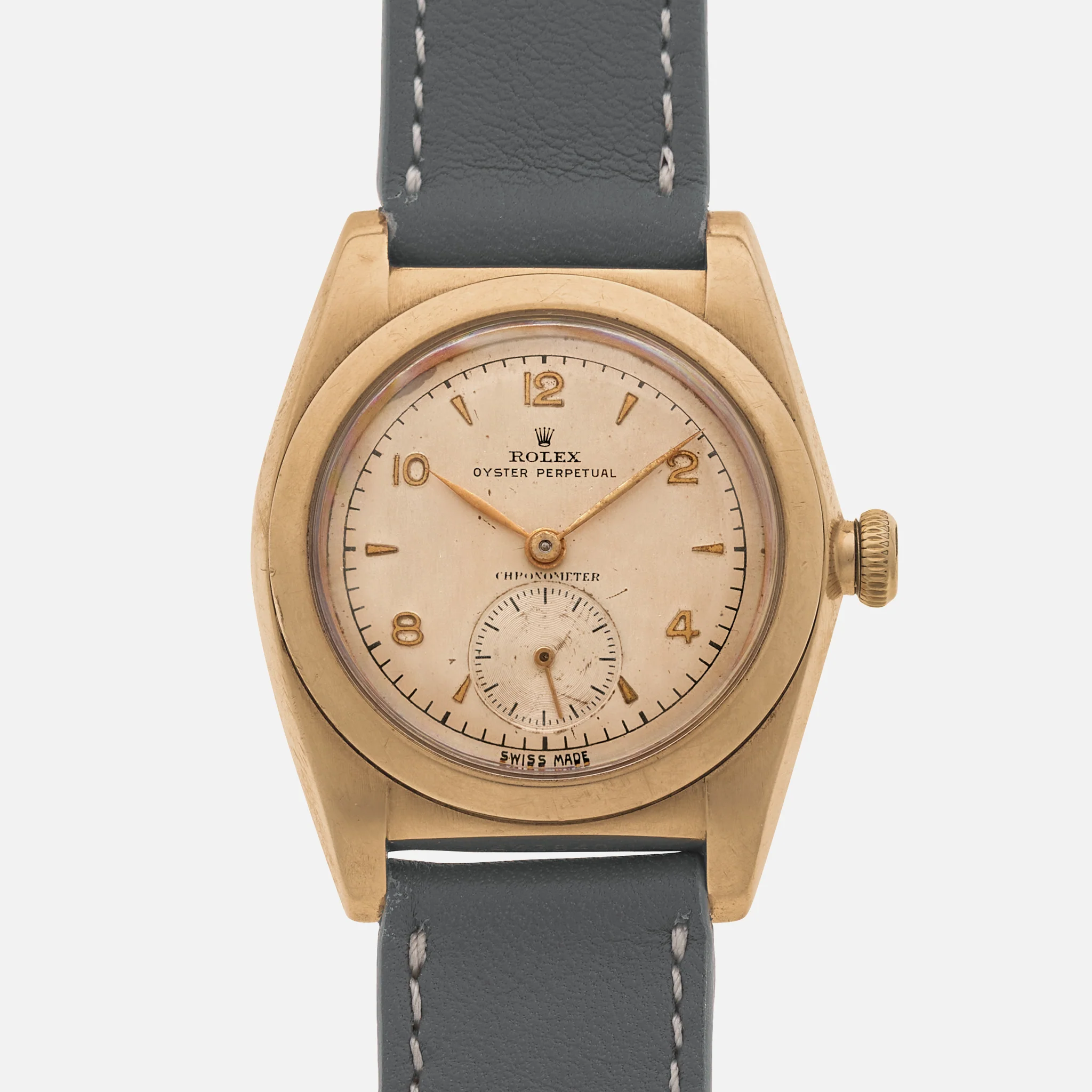 A vintage Rolex Oyster Perpetual wristwatch featuring a 3130 movement, gold case, cream dial, and dark leather strap.