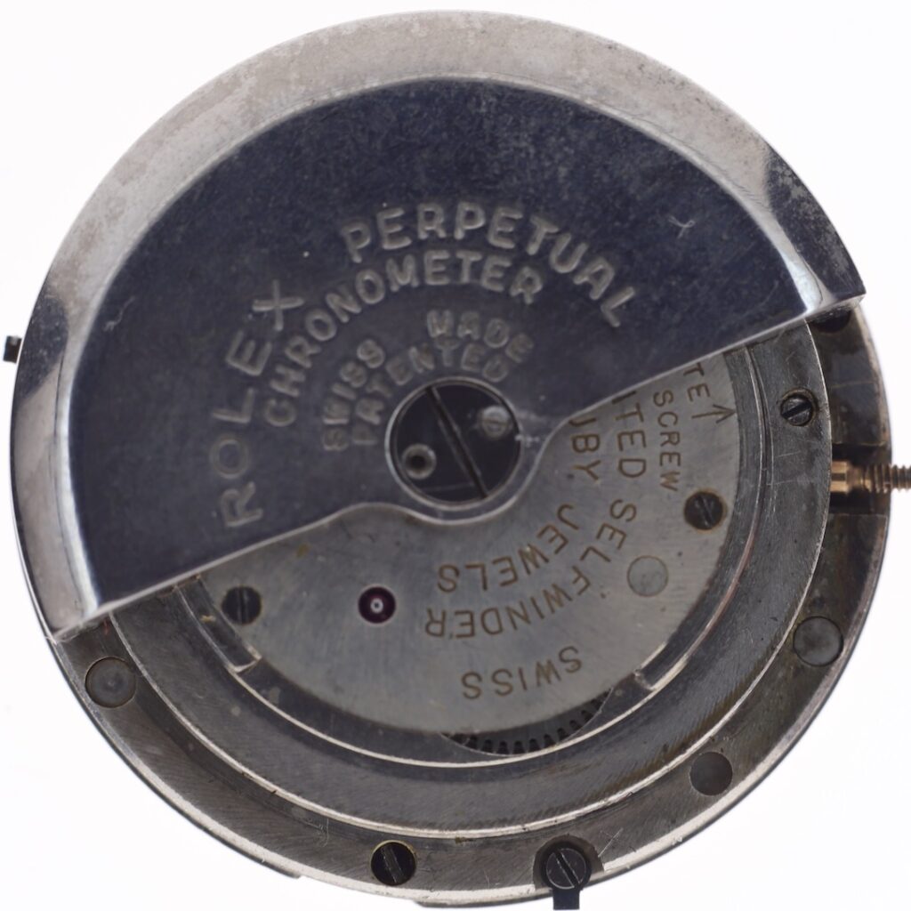 Close-up of a Rolex Perpetual Chronometer watch movement showing engraved text and mechanical parts.