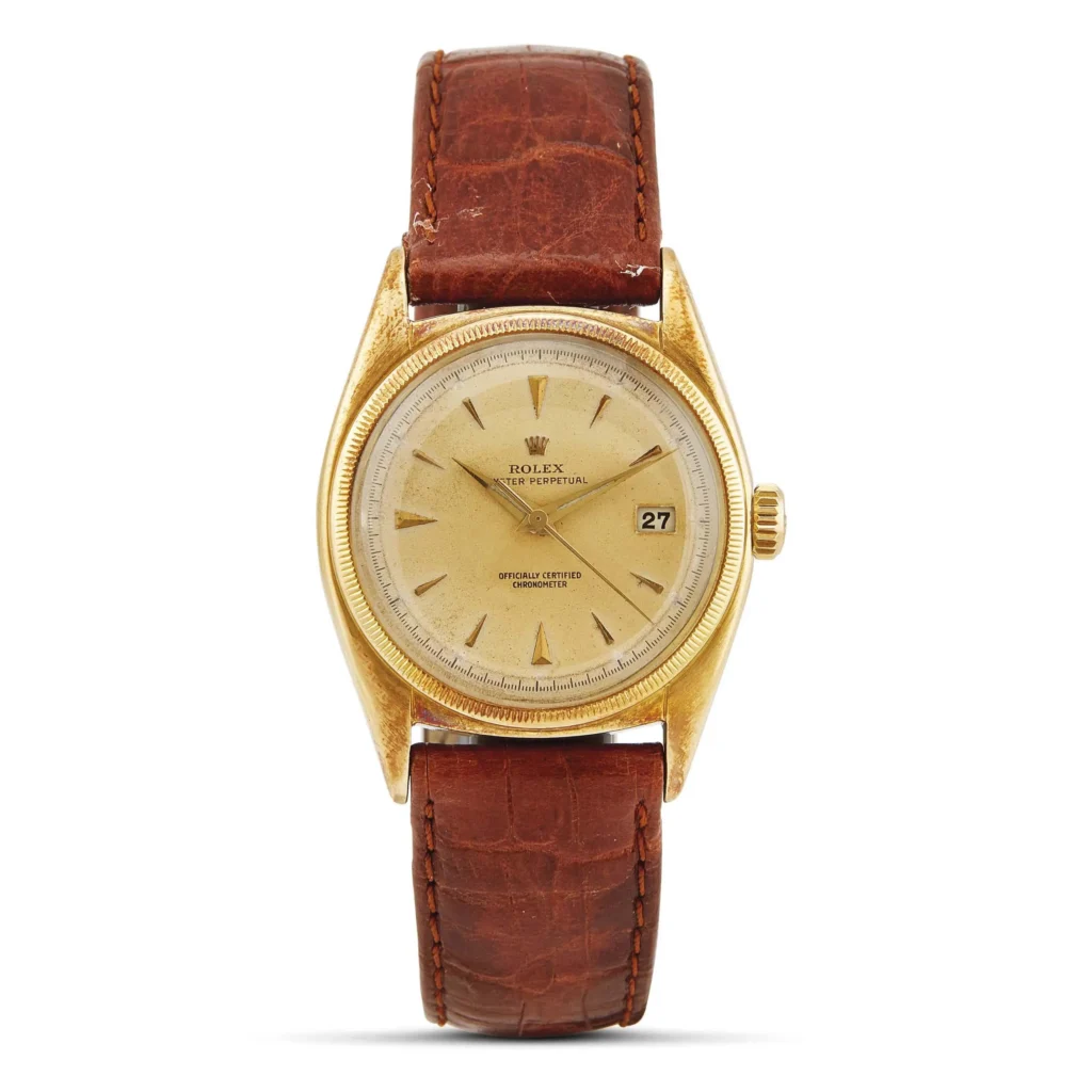 Gold Rolex Oyster Perpetual 6075 wristwatch with a brown leather strap and a date display on the right side of the dial.