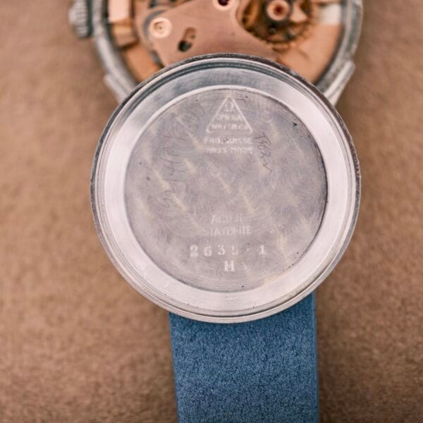 A close-up of an Omega Automatic Bumper 2635 Cal. 351 wristwatch with the case back removed, showing its inner markings and distinctive automatic movement.