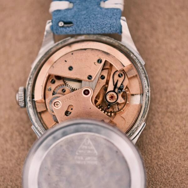 Close-up of the Omega Automatic Bumper 2635 Cal. 351 wristwatch’s exposed mechanical movement, blue strap, and removed back cover.