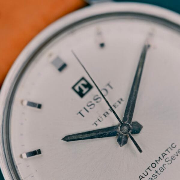 Close-up of a Tissot Automatic Seastar Seven Turler wristwatch with silver hands and markers on a white dial, featuring the Turler signature.