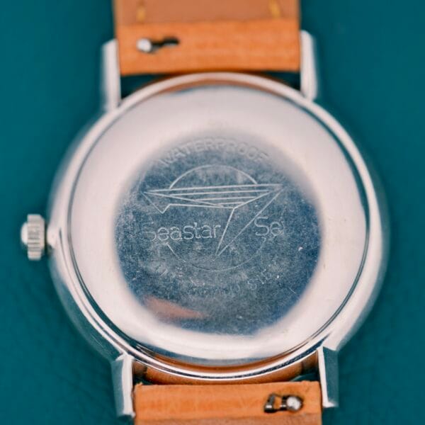 The back of a Tissot Automatic Seastar Seven Turler watch features an engraved logo and Turler text on the metal case, paired with a brown leather strap.
