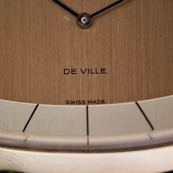 Close-up of the Omega Deville 151.0051 TV Case watch face, featuring DE VILLE and SWISS MADE text on a brushed gold background and the elegant TV Case design.