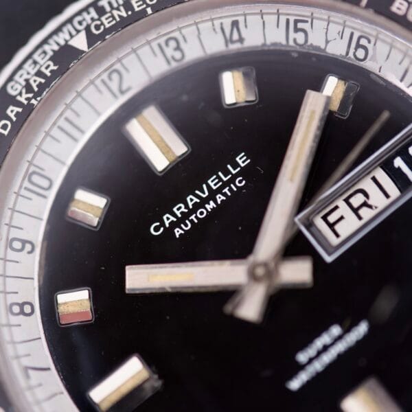 Close-up of a Caravelle Worldtimer Ref. 753 Day/Date automatic wristwatch displaying the time at 3:15 and showing Friday the 11th on the Day/Date feature.