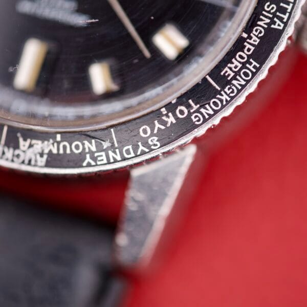 Close-up of a Caravelle Worldtimer Ref. 753 Day/Date bezel, featuring city names such as Tokyo, Sydney, and Hong Kong along with classic day/date display and visible vintage wear.