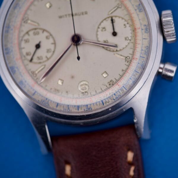 Close-up of a Wittnauer Chronograph Venus 188 wristwatch with a brown leather strap, set against a blue background.