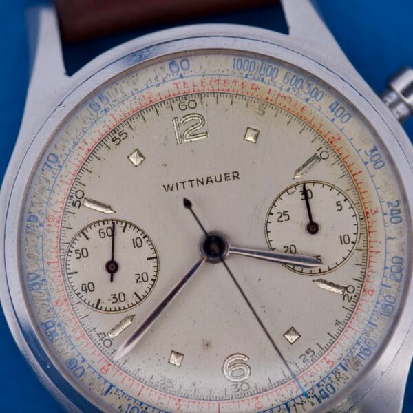 Close-up of a Wittnauer Chronograph Venus 188 wristwatch with a telemeter, displayed against a blue background.