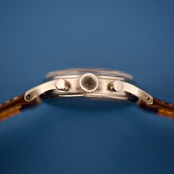 Close-up side view of the Wittnauer Chronograph Venus 188 wristwatch with a leather strap, set against a blue background.