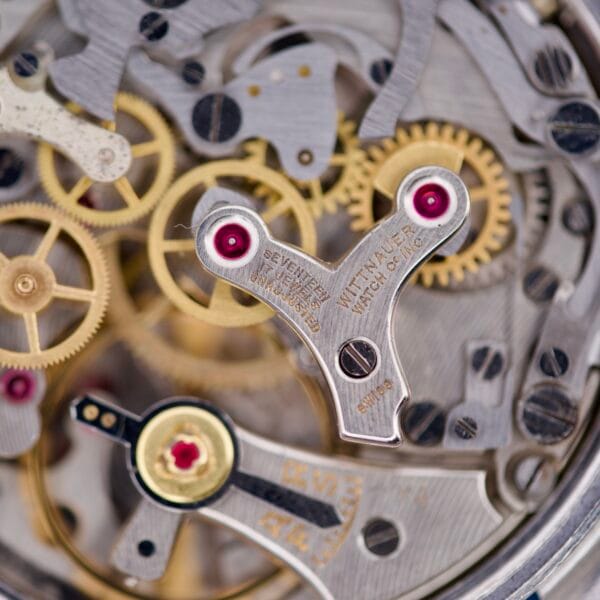 Close-up of detailed gears and red jewel bearings inside the Wittnauer Chronograph Venus 188, showcasing its intricate vintage watch mechanisms.
