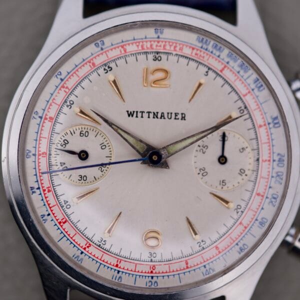 Close-up of a Wittnauer 3256 Chronograph Venus 188 with a silver dial, two subdials, and bold red and blue accents.