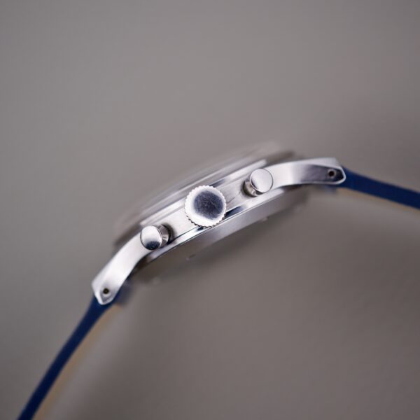 Side view of a Wittnauer 3256 Chronograph Venus 188 wristwatch with a blue strap, showing the crown and two buttons against a gray background.