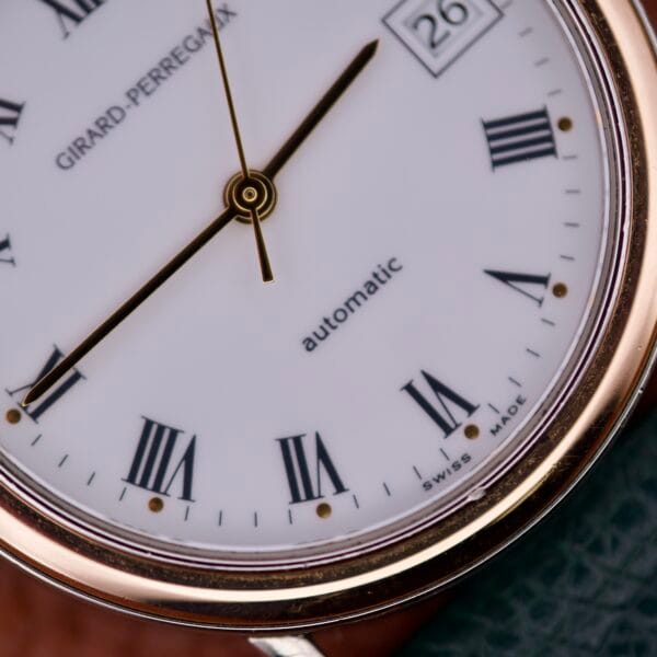 Close-up of the Girard Perregaux Automatic 4797 watch face, featuring Roman numerals, a gold rim, and date display set to 26—a classic automatic timepiece renowned for its elegant design and fine craftsmanship.