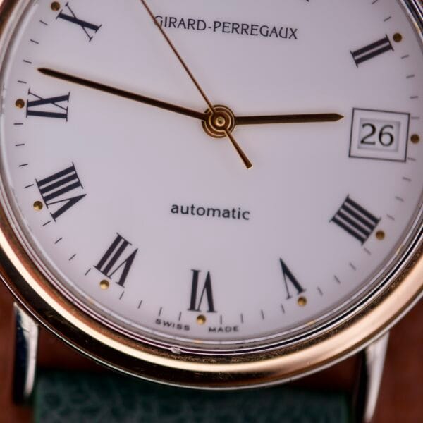 Close-up of the Girard Perregaux Automatic 4797 watch face, highlighting Roman numerals and a date display set to the 26th.