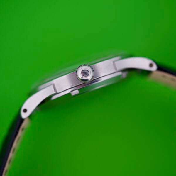 Close-up side view of an Omega Automatic Bumper 2635 Original Strap wristwatch on a bright green background.