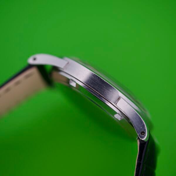 Side view of the Omega Automatic Bumper 2635 with its original strap, displayed against a bright green background.