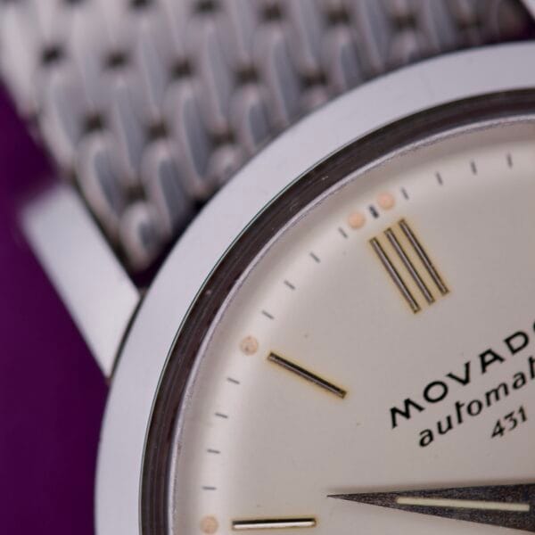 Close-up of the Movado Automatic 431 Stainless Steel watch face featuring gold hour markers and a partial view of its stainless steel band.