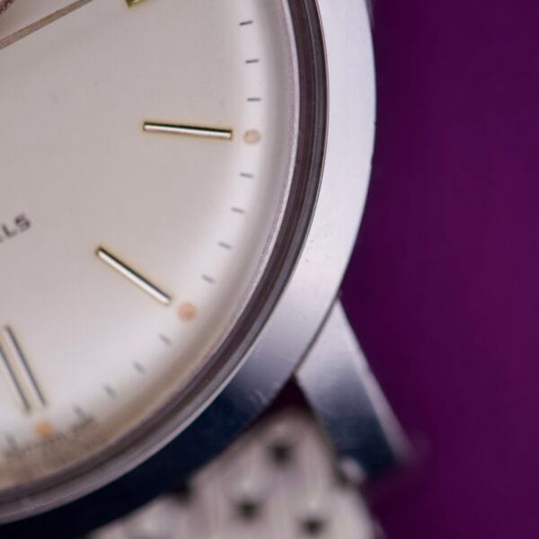 Close-up of the Movado Automatic 431 Stainless Steel watch face with a stainless steel strap set against a purple background.