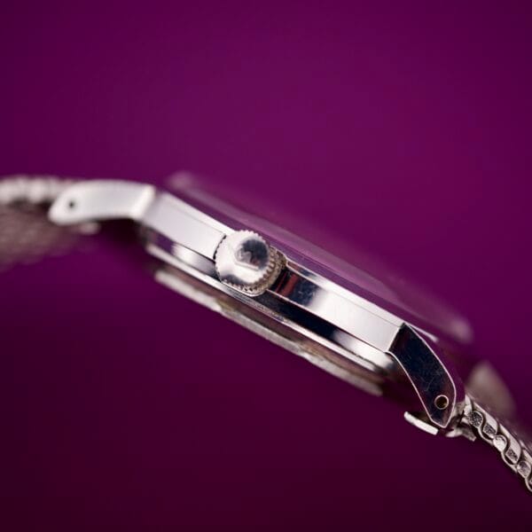 Side view of the Movado Automatic 431 Stainless Steel watch with a metal band, shown against a solid purple background.