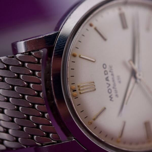 Close-up of the Movado Automatic 431 Stainless Steel wristwatch, featuring a stainless steel mesh band and a white dial.