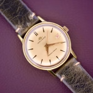 The Movado Tempo-Matic Sub Sea Roulette Date is a gold wristwatch with a black leather strap and a Roulette Date display showing 30 on a purple background.