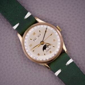 Zodiac Triple Calendar Moonphase Cal. 12S wristwatch in gold with green strap, featuring day, date, and moonphase displays on a textured dial.
