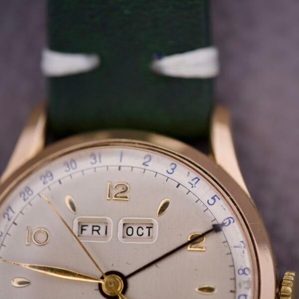 Close-up of the Zodiac Triple Calendar Moonphase Cal. 12S wristwatch displaying FRI and OCT, with a green leather strap.