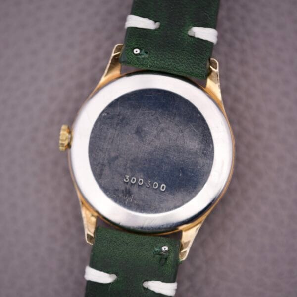 Back of a Zodiac Triple Calendar Moonphase Cal. 12S with green strap and the number 300300 engraved on its metal case.