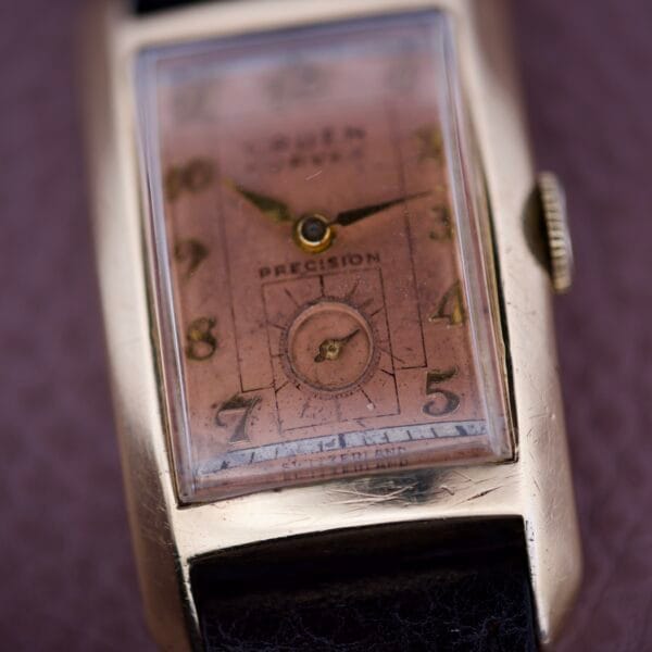 Close-up of the Gruen Curvex Precision Salmon Dial vintage rectangular wristwatch, featuring expert craftsmanship with a gold case, salmon dial, and leather strap.