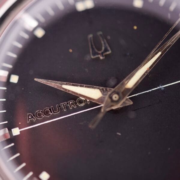 Close-up of the Bulova Accutron 218 Black Dial watch face, highlighting its hands and a portion of the black dial.