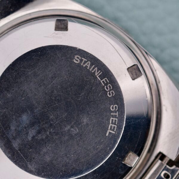 Close-up of a Wittnauer Diver Bakelite Bezel 1002-W100 watch back engraved with STAINLESS STEEL on a metallic surface, showing its distinctive reference.