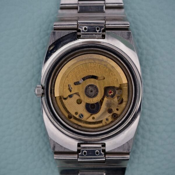 Close-up of the Wittnauer Diver Bakelite Bezel 1002-W100’s exposed mechanical movement, highlighting its intricate gears and signature Bakelite bezel against a light blue background.