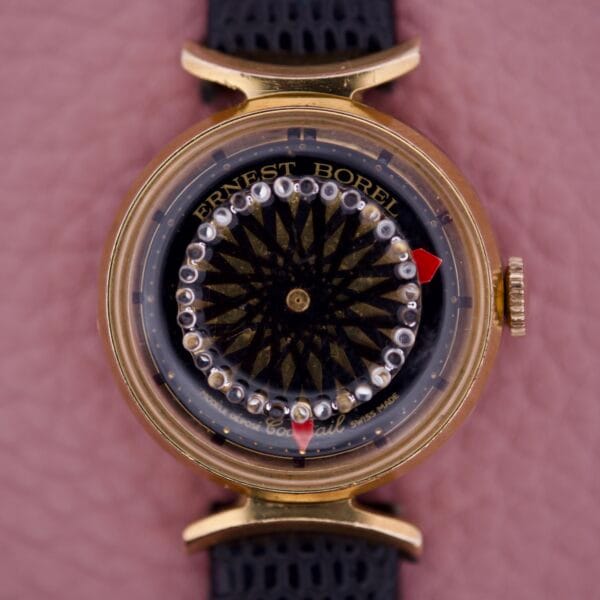 The Ernest Borel Kaleidoscope Cocktail 17 Jewels wristwatch features a distinctive kaleidoscope dial, 17-jewel movement, and gold case, showcased on a textured background.