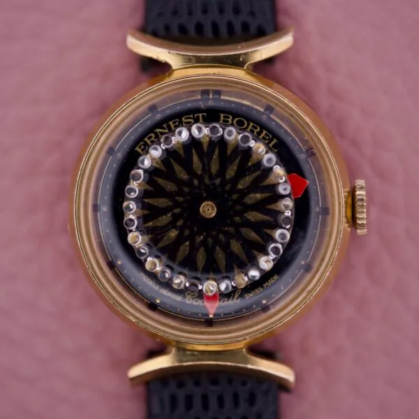 The Ernest Borel Kaleidoscope Cocktail 17 Jewels wristwatch features a distinctive kaleidoscope dial, 17-jewel movement, and gold case, showcased on a textured background.