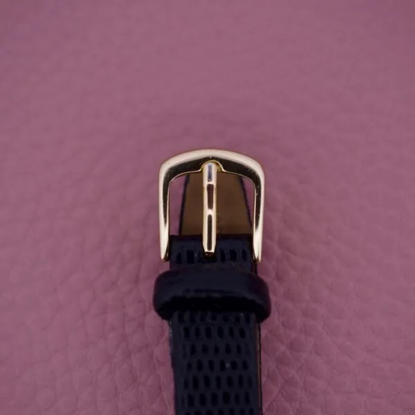 Black textured watch strap with a gold buckle, ideal for pairing with the Ernest Borel Kaleidoscope Cocktail 17 Jewels, shown on a mauve textured background.