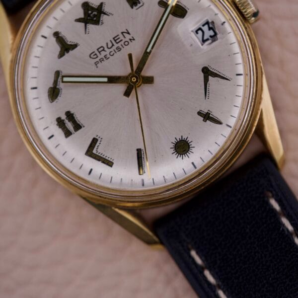 Close-up of a Gruen Precision 510 Date Masonic Dial watch, showcasing unique Masonic symbols on the face in place of numbers and a black leather strap.