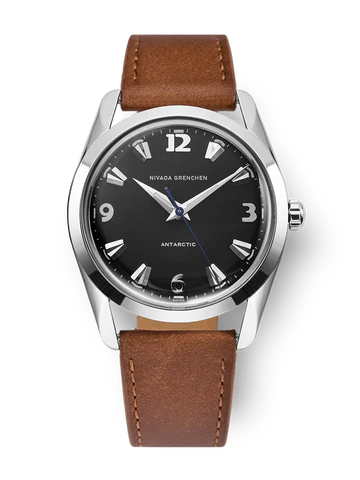 The Nivada Grenchen Antarctic wristwatch features a black dial, silver markers, and a brown leather strap—model 35002M16.